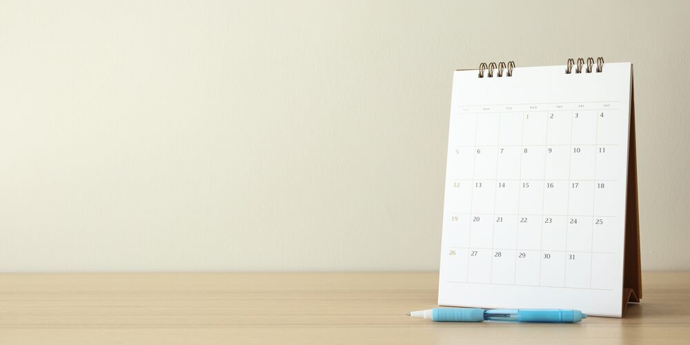 Calendario de escritorio con un bolígrafo sobre una mesa de madera