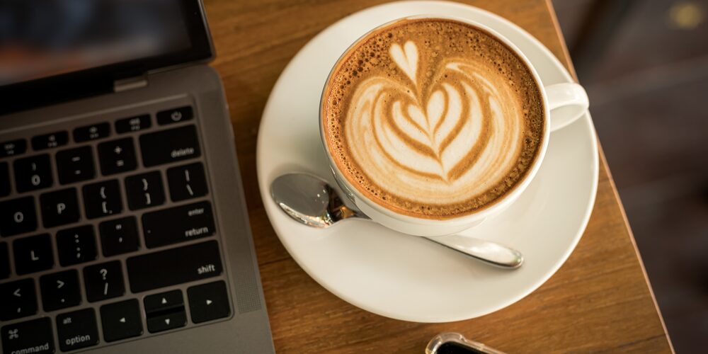 Mesa de trabajo con ordenador portátil, café y teléfono móvil